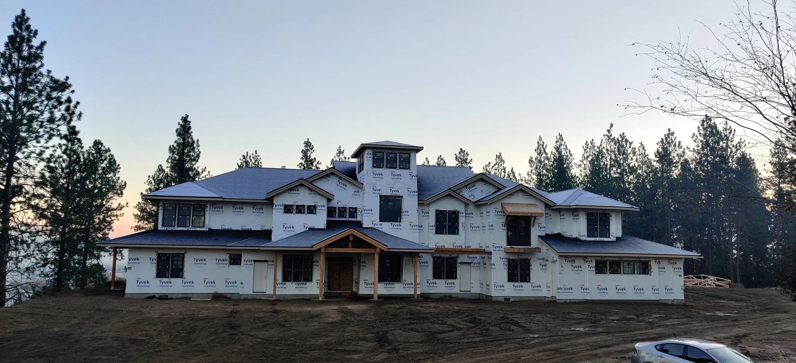 Large custom home exterior showing broad framing progress across the facade