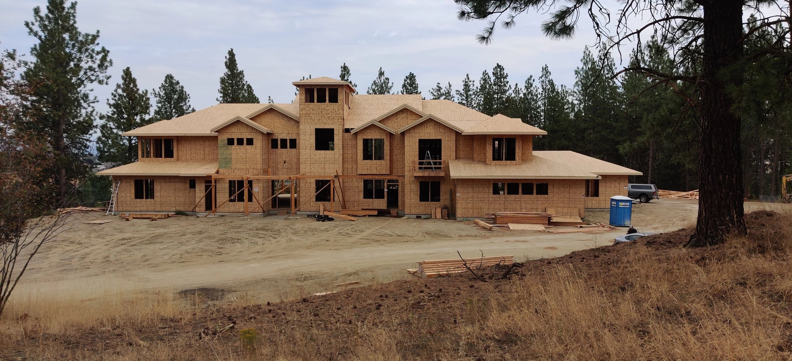 Woodland custom home framing with exposed roof and exterior wall progress